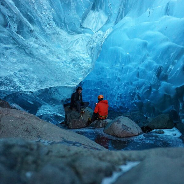 A guest chatting with their expert ice cave and glacier guide about the formation of the ice cave their sitting in on a full day glacier exploration hiking tour.
